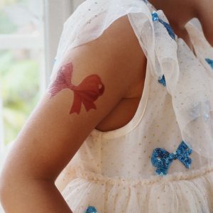 sfeerfoto van een arm van een kindje met daarop een roze glitter tattoo in de vorm van een strikje